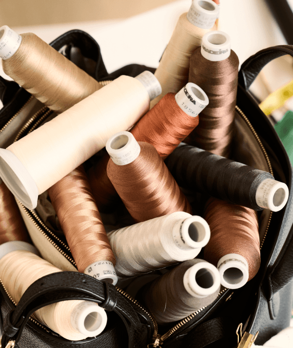 Premium Madeira embroidery threads in neutral tones inside a black leather bag